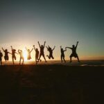 silhouette photography of group of people jumping during golden time