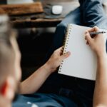 man lying writing in notebook