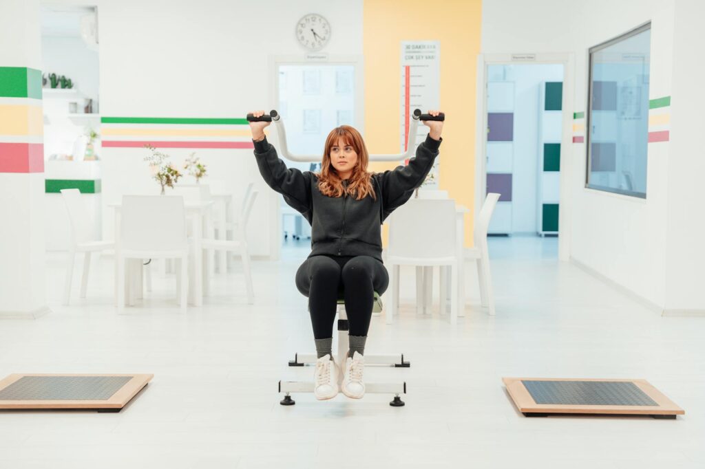 woman in sweatshirt and yoga pants exercising at pilates gym