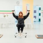 woman in sweatshirt and yoga pants exercising at pilates gym